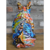 Colourful graffiti-style sitting bulldog sculpture with vibrant abstract patterns on a wooden surface against a brick wall.