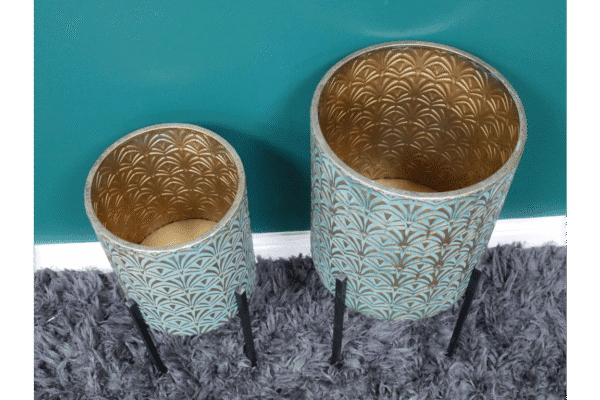 Set of two geometric metal planters with gold interior, small size, 52cm, on black metal stands against teal wall and grey carpet.