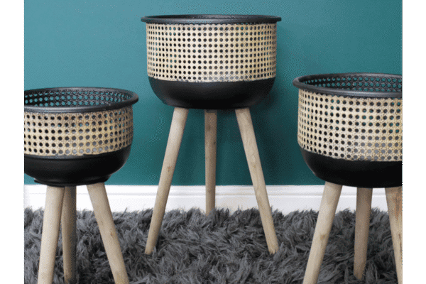 Set of three modern plant stands with woven baskets and wooden legs, ideal for home decorating and displaying plants.