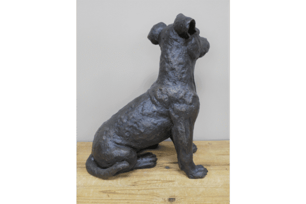 Gunmetal metallic sitting dog sculpture, detailed and textured, displayed on a wooden surface.
