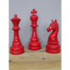 Red decorative chess pieces including a king, queen, and knight on a wooden surface.