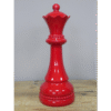Red decorative chess queen piece made of glossy material, standing on a wooden surface.