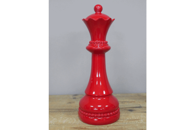 Red decorative chess queen piece made of glossy material, standing on a wooden surface.