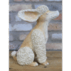 Decorative ceramic sitting poodle sculpture with curly fur and large ears, placed on a wooden surface against a brick wall background.
