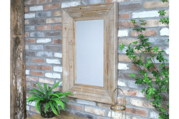 Wooden rectangular mirror with a rustic frame mounted on a brick wall, surrounded by green plants and decorative items.