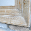 Close-up of a wooden rectangular mirror frame showing natural wood grain and weathered finish.