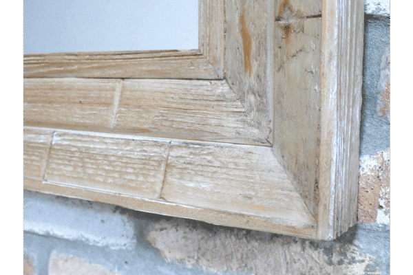 Close-up of a wooden rectangular mirror frame showing natural wood grain and weathered finish.