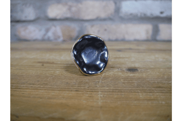 Close-up of a black ceramic cabinet knob with a glossy finish on a wooden surface.