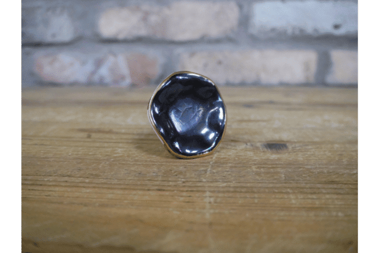 Close-up of a black ceramic cabinet knob with a glossy finish on a wooden surface.