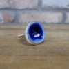 Ceramic dark blue cabinet knob with a glossy finish on a wooden surface.