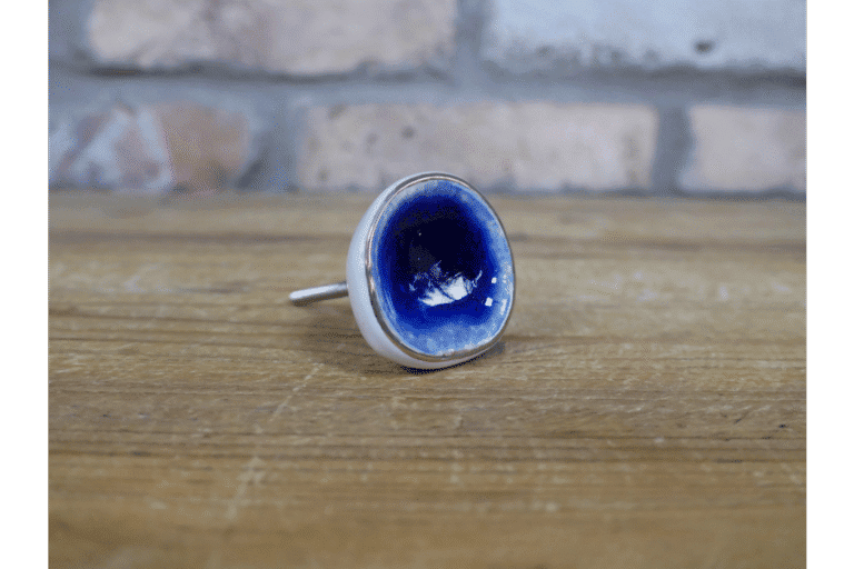 Ceramic dark blue cabinet knob with a glossy finish on a wooden surface.