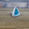 Ceramic turquoise cabinet knob with a triangular shape and silver backing, ideal for home decorating projects.