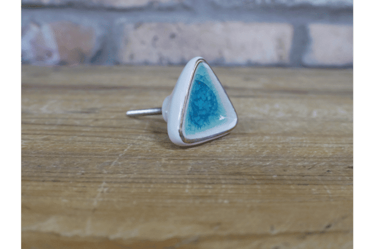 Ceramic turquoise cabinet knob with a triangular shape and silver backing, ideal for home decorating projects.