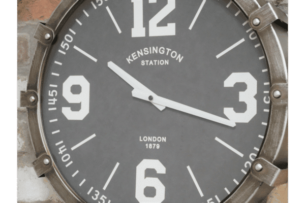 Industrial-style clock with large white numerals and metal frame, mounted on a brick wall, showcasing a vintage design.