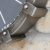 Close-up of an industrial-style cog clock with metallic finish and rivet details, mounted on a textured brick wall.