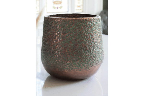Close-up of a textured aluminium pitted planter with a weathered finish, suitable for outdoor or indoor garden decor.