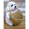 Cute ceramic dog figurine holding a woven basket with a brick wall background.