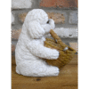 Decorative ceramic dog figurine holding a small woven basket, placed on a wooden surface against a brick wall background.