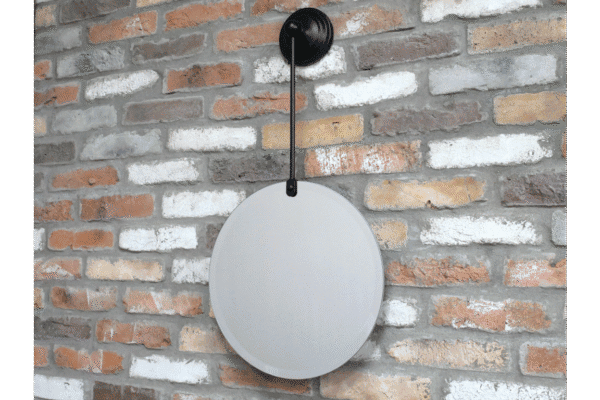 Round hanging mirror with black wall mount on a brick wall, modern home decor.