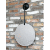 Round hanging mirror with black mount on a brick wall, modern home decor accessory.
