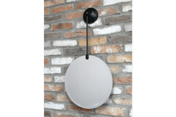 Round hanging mirror with black mount on a brick wall, modern home decor accessory.