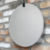 Round hanging mirror with a sleek, modern design mounted on a rustic brick wall.