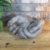 Weathered hands ornament made of stone, placed on a wooden surface with a brick wall background, suitable for home decorating.