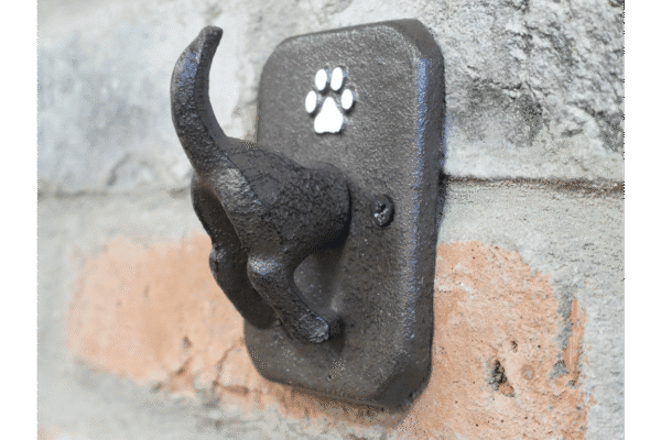 Dog coat hook mounted on a brick wall, designed for hanging pet accessories.