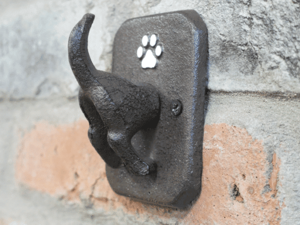Dog coat hook mounted on a brick wall, featuring a paw print design for pet accessories storage.