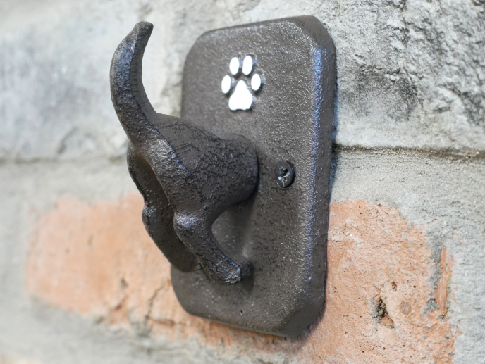 Dog coat hook mounted on a brick wall, featuring a paw print design for pet accessories storage.