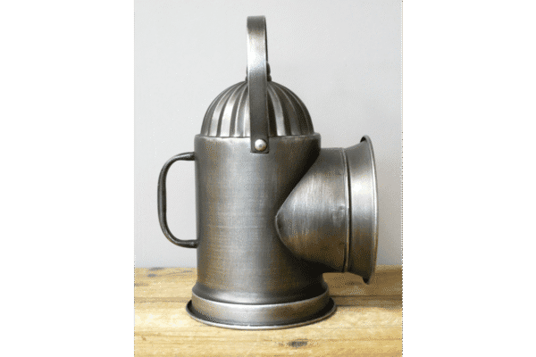 Vintage metal lantern with a handle and a large conical opening, placed on a wooden surface.