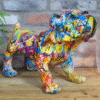 Colourful graffiti-style dog sculpture on wooden surface with brick wall background.