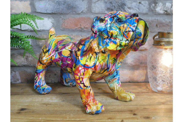 Colourful graffiti-style dog sculpture on wooden surface with brick wall background.