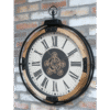Industrial-style wall clock with visible gears and Roman numerals, mounted on a brick wall.