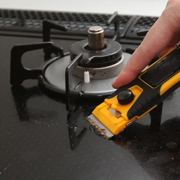 Olfa Pro Glass Scraper GSR-2 with ergonomic handle and safety cover in use on hob.