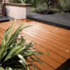 Beautiful wooden decking area with lush green plants and modern outdoor furniture, ideal for garden relaxation and outdoor entertaining.