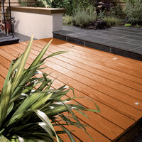 Beautiful wooden decking area with lush green plants and modern outdoor furniture, ideal for garden relaxation and outdoor entertaining.