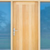 Close-up of a wooden exterior door with glass panels and a silver handle, set in a modern building with blue-tinted glass windows.