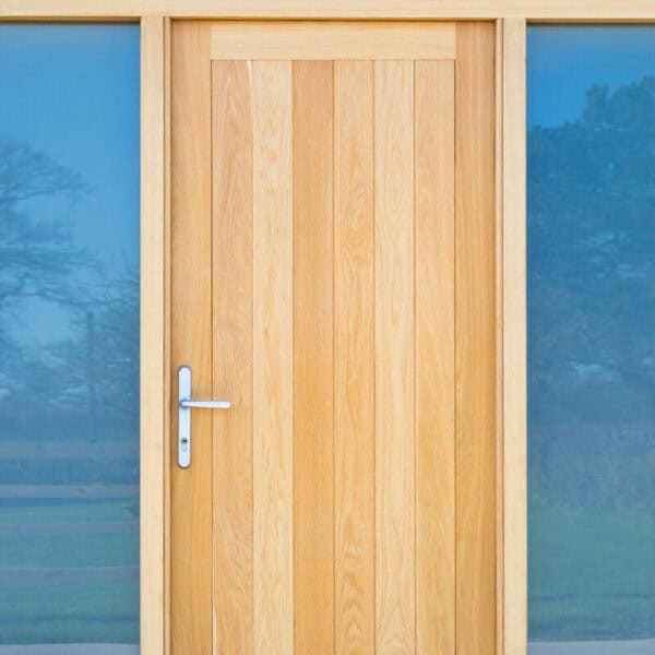 Close-up of a wooden exterior door with glass panels and a silver handle, set in a modern building with blue-tinted glass windows.