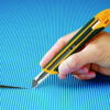 Olfa Snap Off Knife 9mm XA-1 with autolock and ergonomic handle. Showingf knife cutting through square paper.