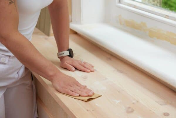 Person sanding wooden surface using Fit For The Job sandpaper sheet